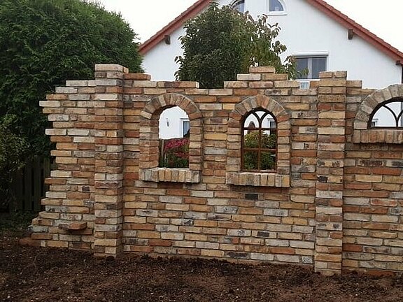 Ruinenmauer aus alten Ziegelsteinen als Dekorationselement im Garten